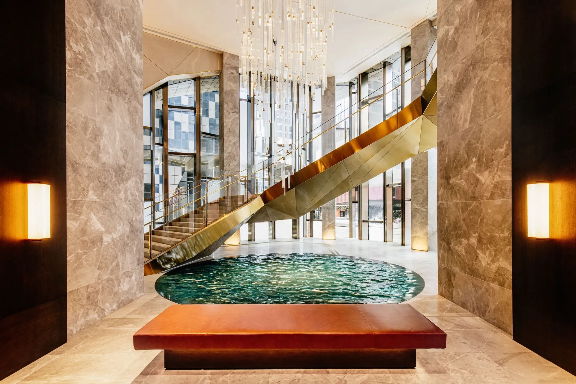 A curved staircase sweeps around a pool of water in the dramatic lobby of the Ritz-Carlton Hotel Melbourne