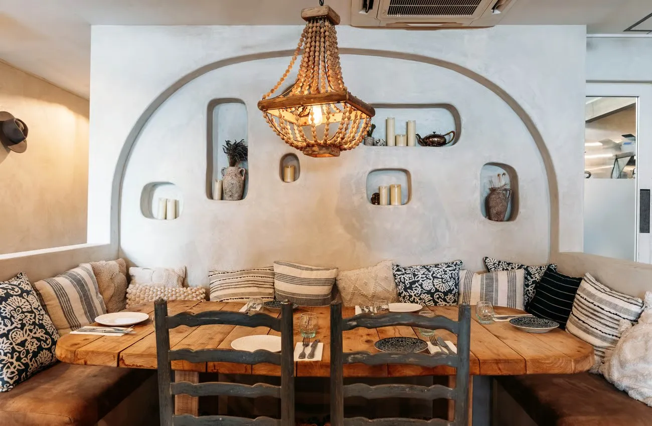 A wooden table with booth seating piled high with cushions at Sofi restaurant in Wanaka.